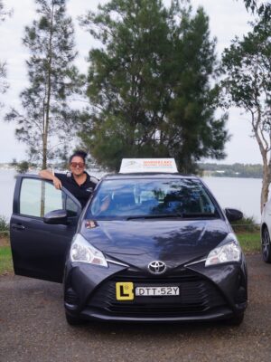 A man standing next to a car in front of water.