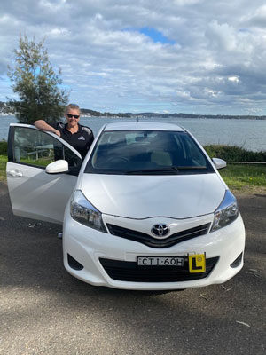 A man standing next to a white car.