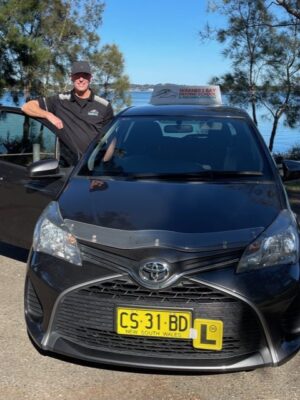 A man standing next to a black car.